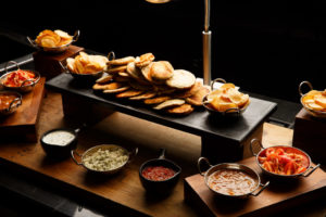 A food counter full of delicious looking dips and salsas with nan breads and poppadums as part of mercure hotels meeting food offering